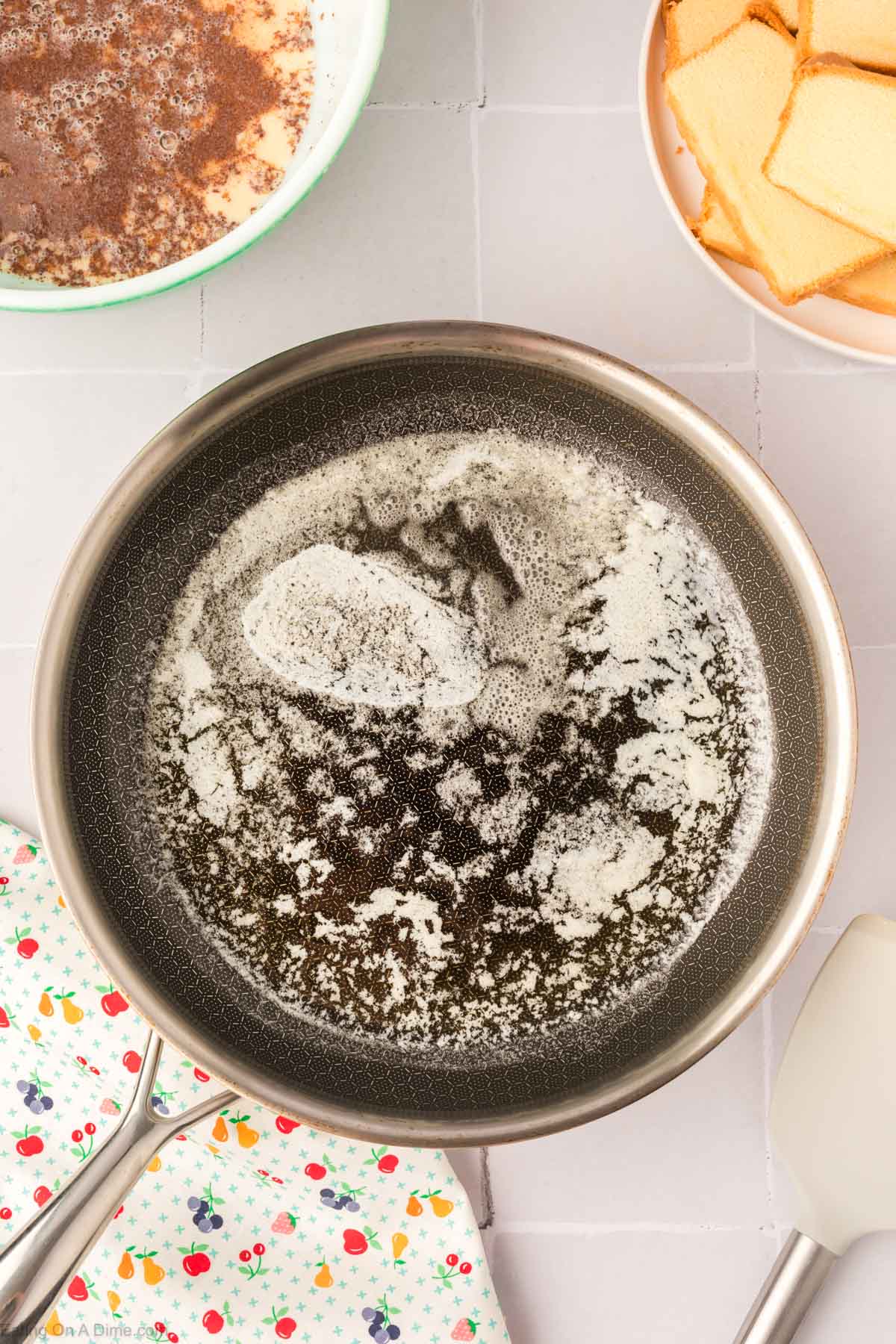 Melted butter in a skillet with a bowl of cinnamon mixture and pound cake slices stacked on a plate on the side