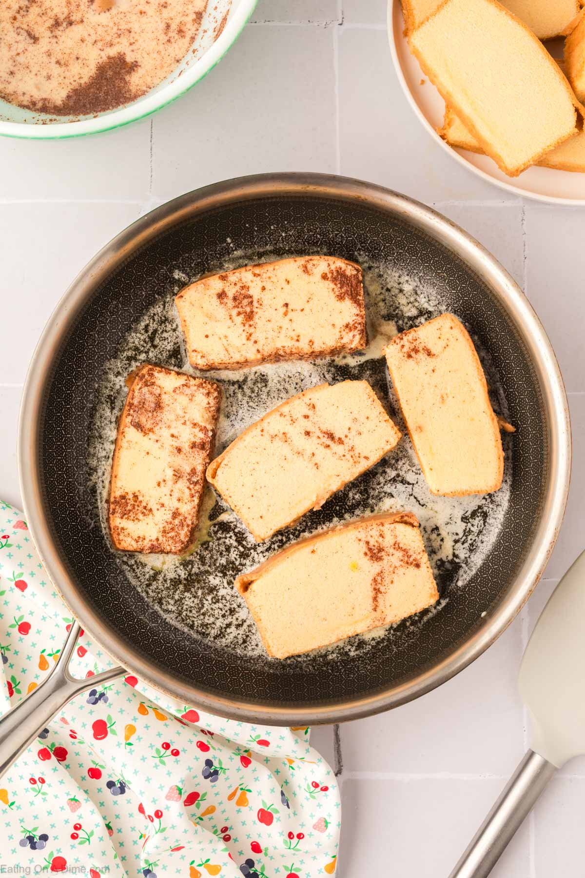 Placing the cinnamon covered pound cake slices in a skillet with melted butter