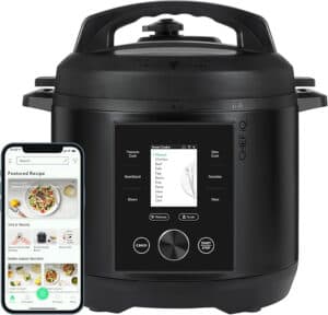 A black Chef iQ smart pressure cooker, one of the best multicookers, with a digital display sits next to a smartphone. The phone screen shows a cooking app with recipes and cooking tips.