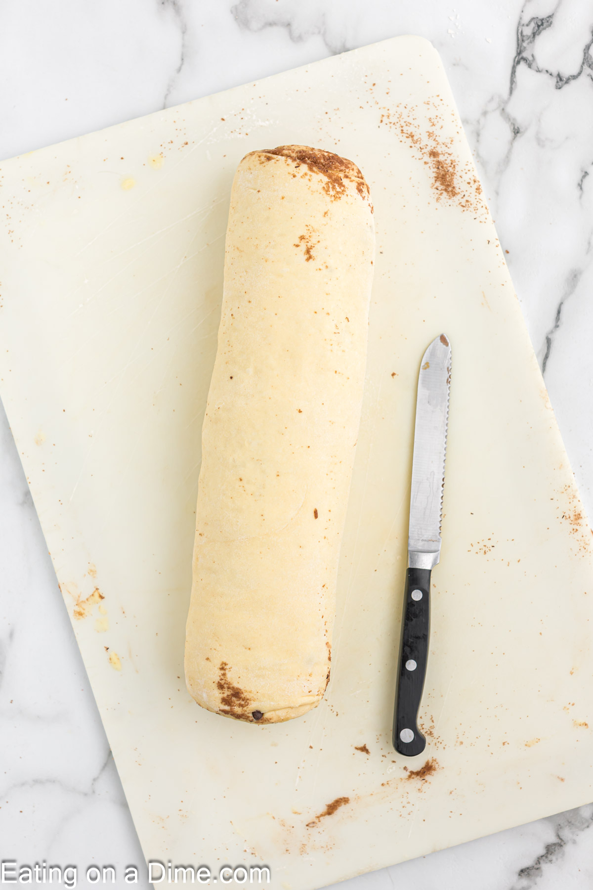 Dough rolled into a tube shaped on a cutting with a knife on the side