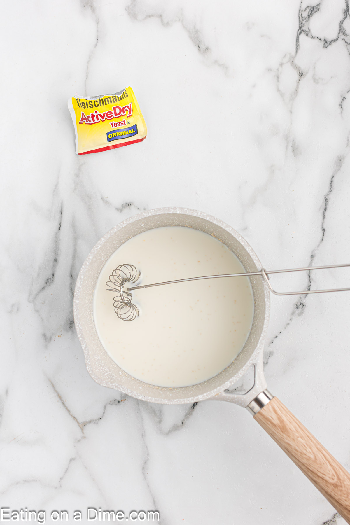 Whisking milk and yeast together in a saucepan