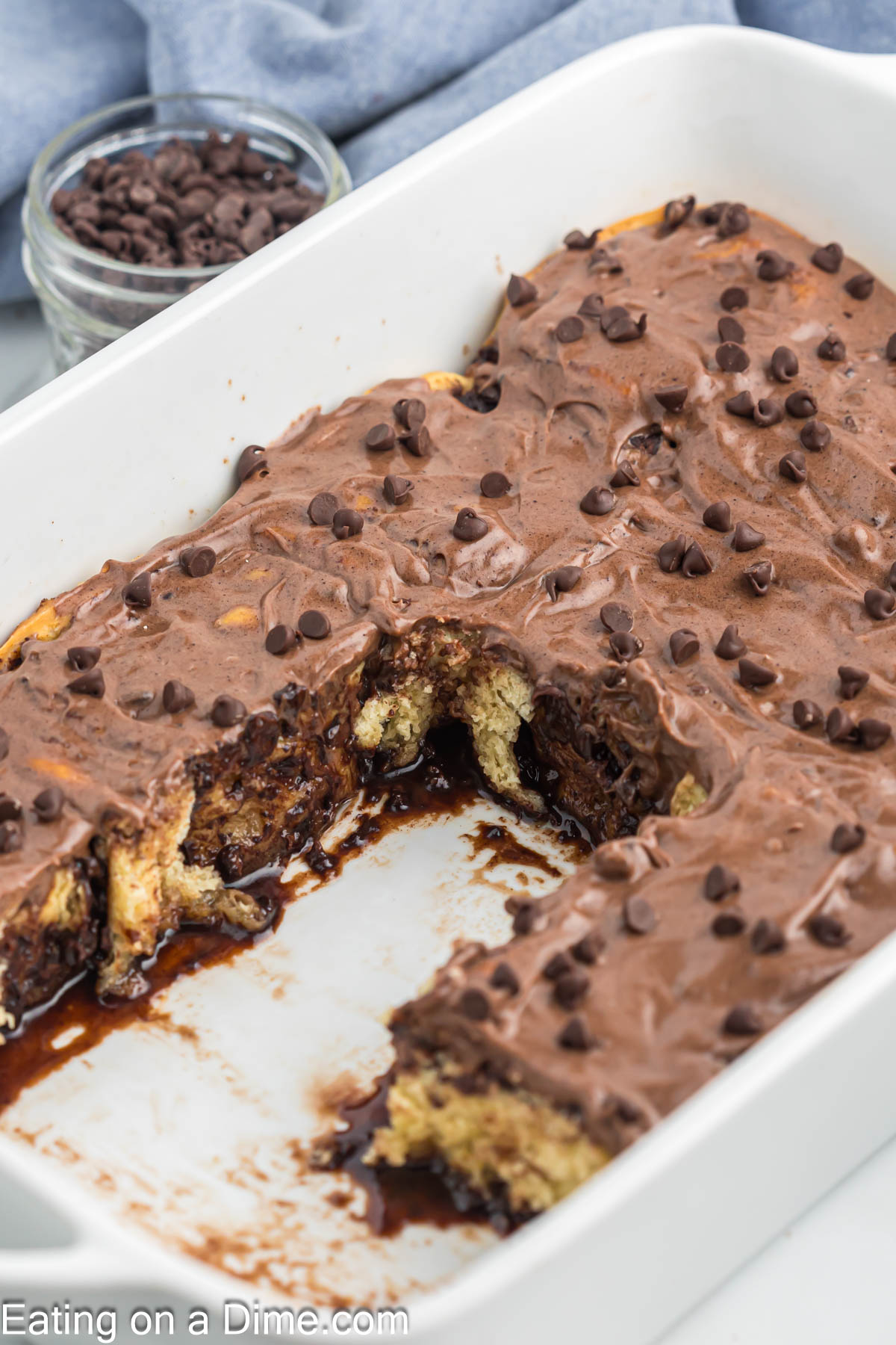 Chocolate Chip cinnamon rolls baked in a baking dish topped with chocolate chip frosting 