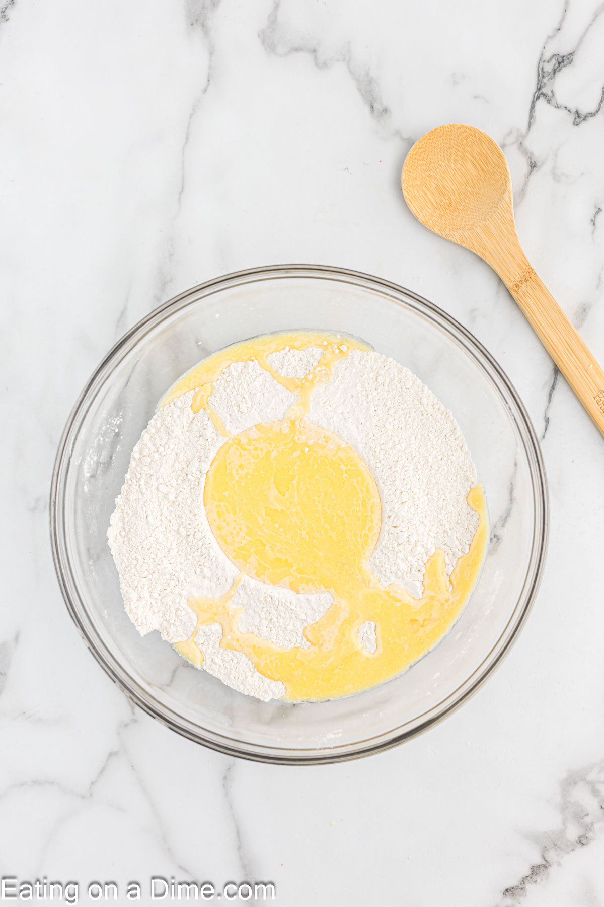 Butter mixture with the flour mixture in a bowl with a wooden spoon