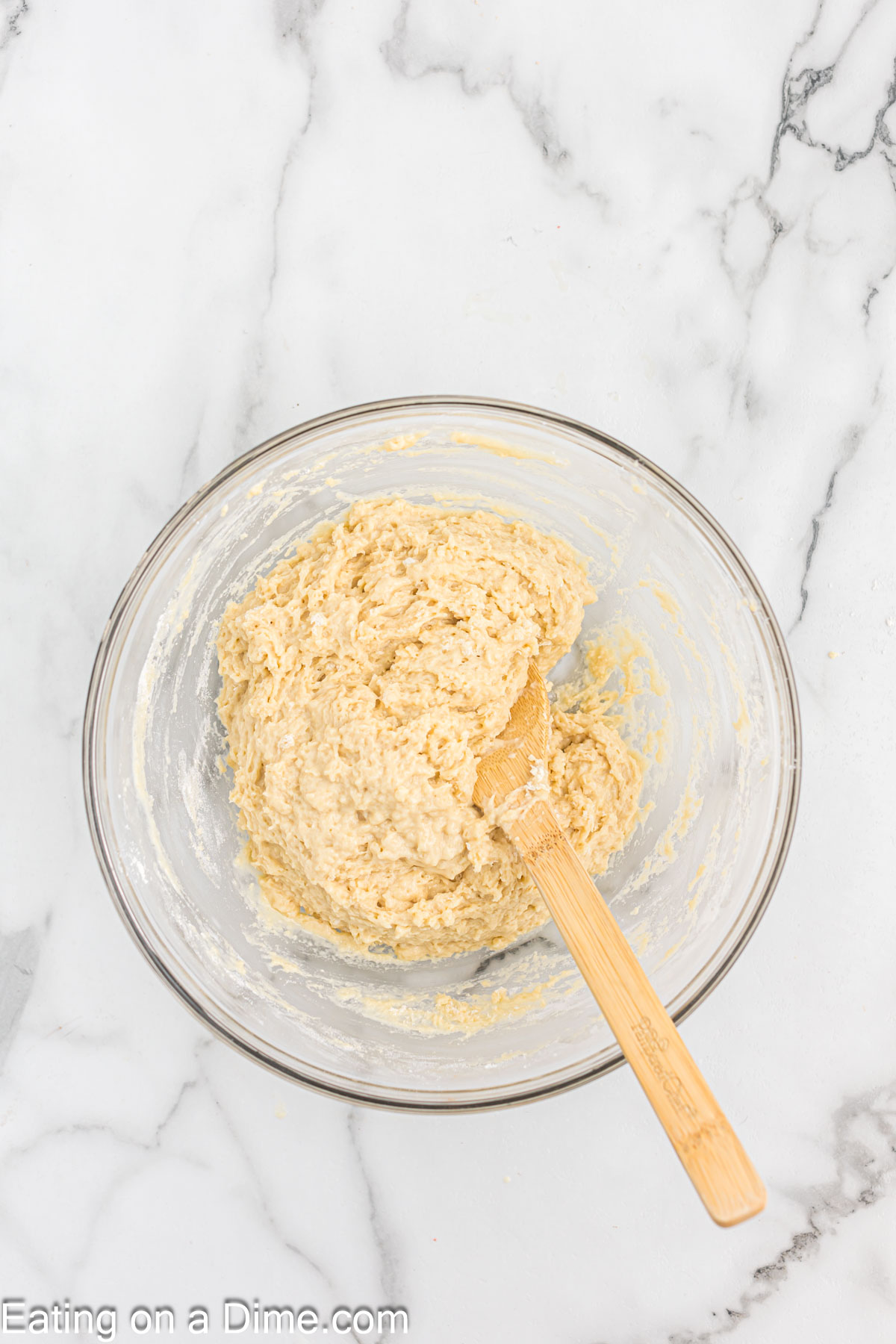 Dough combined together in a bowl with a wooden spoon