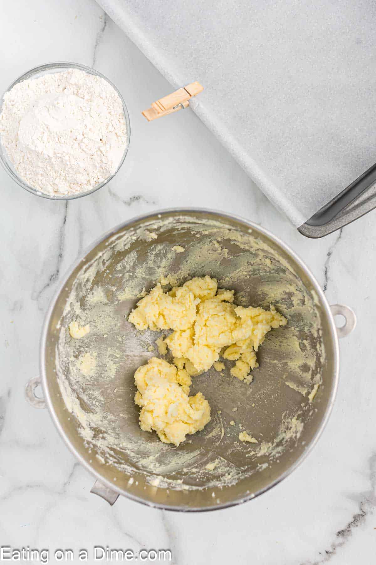 Beating butter and sugar in a bowl with a small bowl of flour on the side