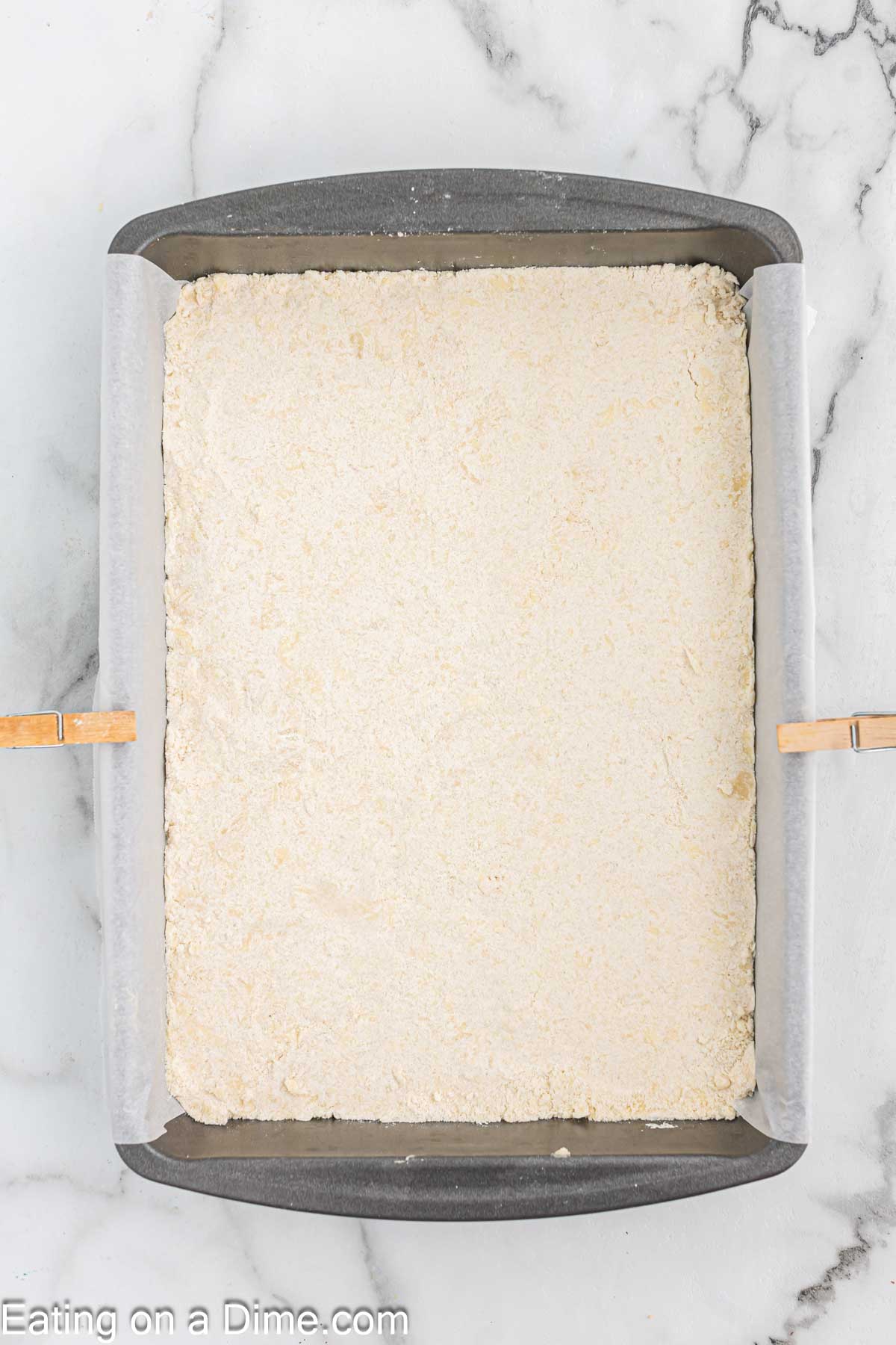 Pressing the flour mixture into the baking dish lined with parchment paper