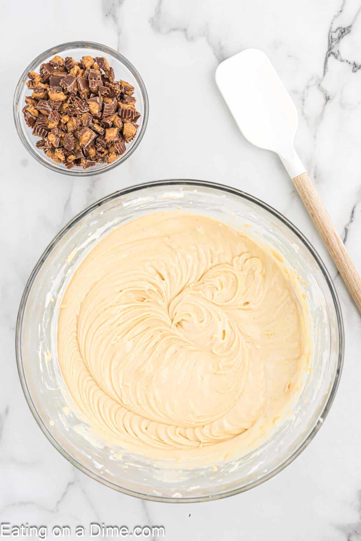 Cheesecake batter in a bowl with a small bowl of chopped Reese's Peanut butter Cups