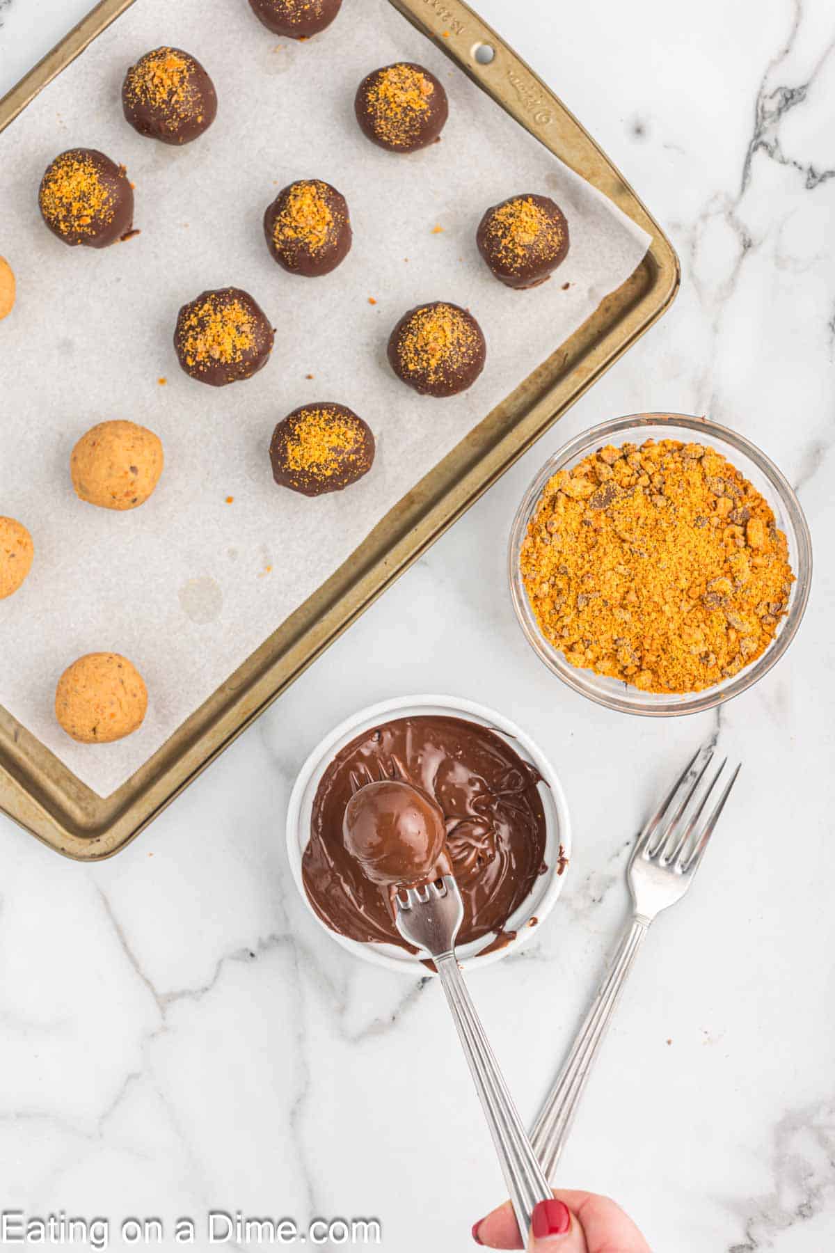 Dipping butterfinger balls into melted chocolate and putting them on the baking sheet lined with parchment paper