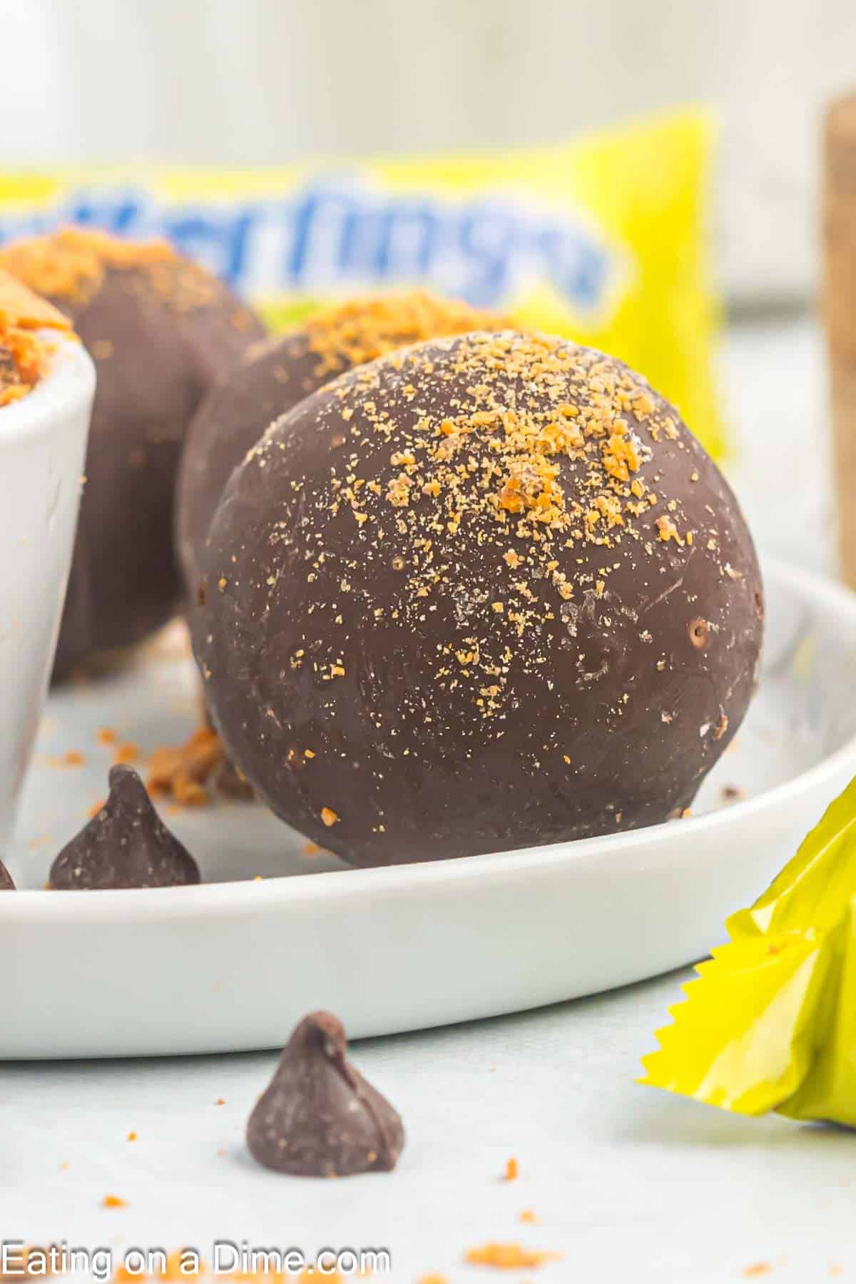 Melted chocolate covered peanut butter balls topped with crushed butterfinger on a plate