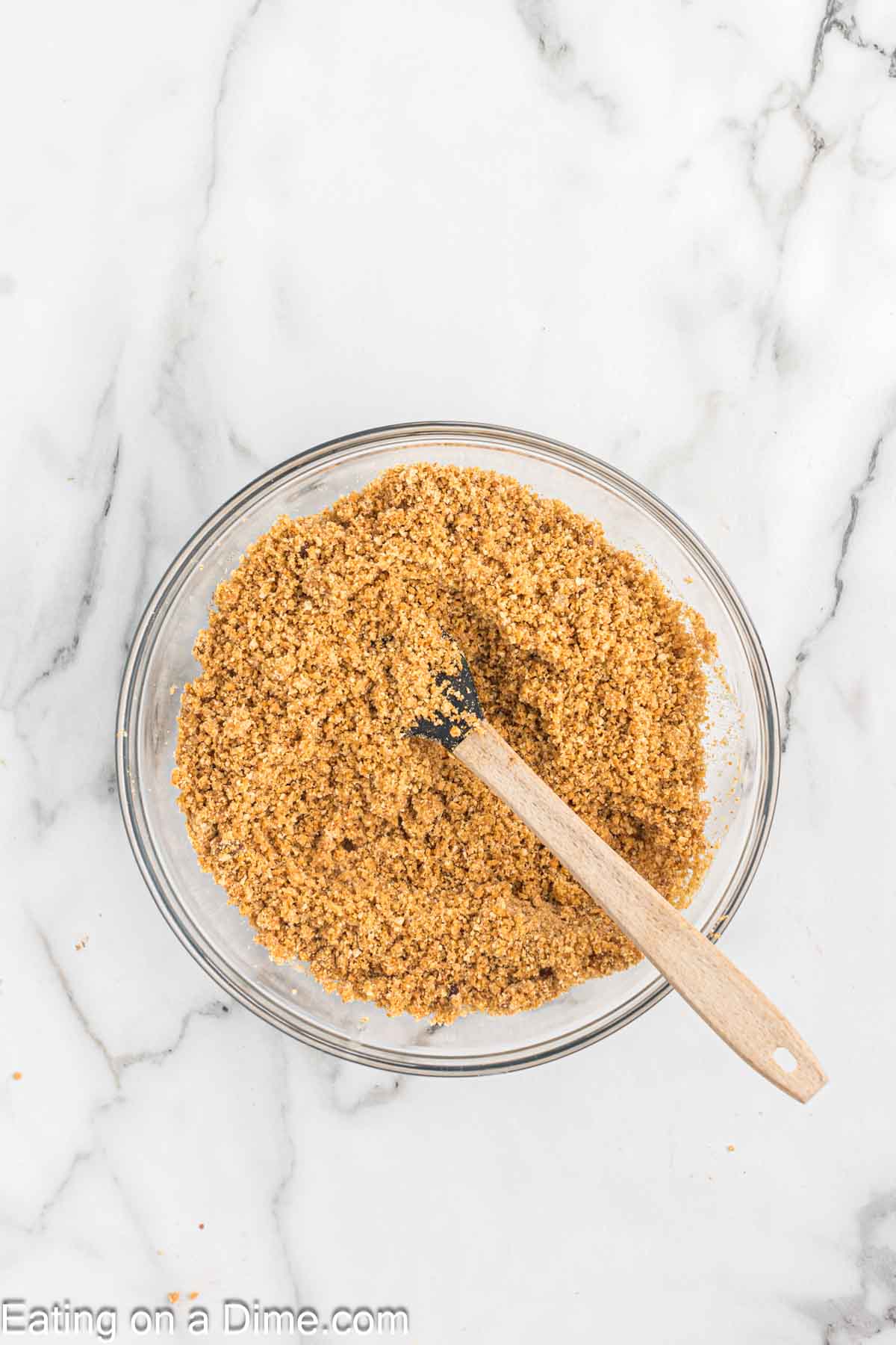 Mixing the graham cracker crumbs with the other ingredients in a bowl with a wooden spoon