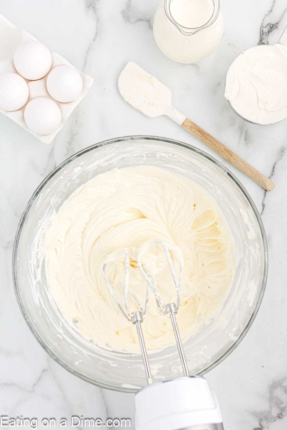 Cream cheese mixing with sugar and vanilla extract in a bowl with a hand mixer