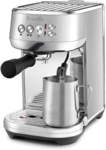 A stainless steel espresso machine, hailed as one of the best budget espresso machines, features a steam wand frothing milk in a metal jug. The front panel is equipped with several buttons and indicator lights for easy operation.