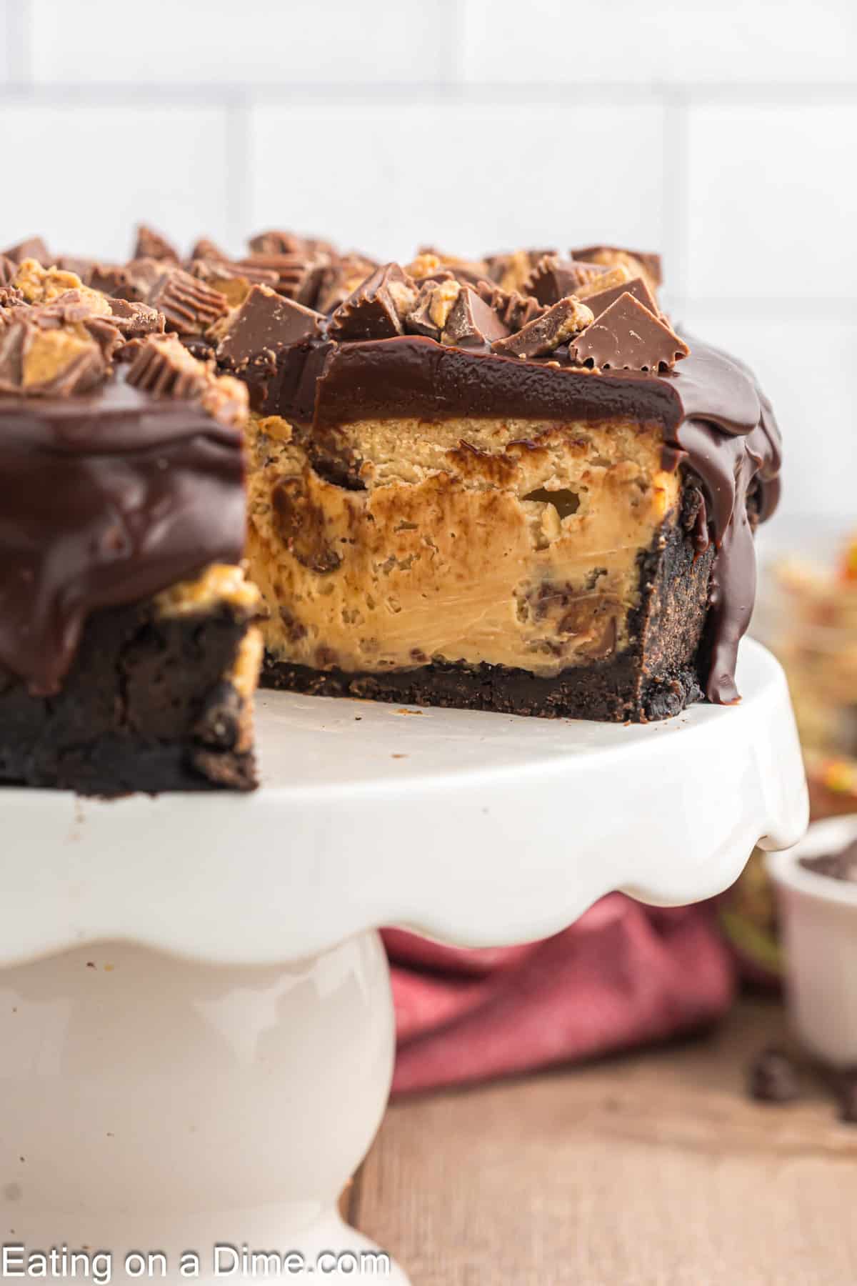 Reese's Cheesecake with a slice missing on a cake stand