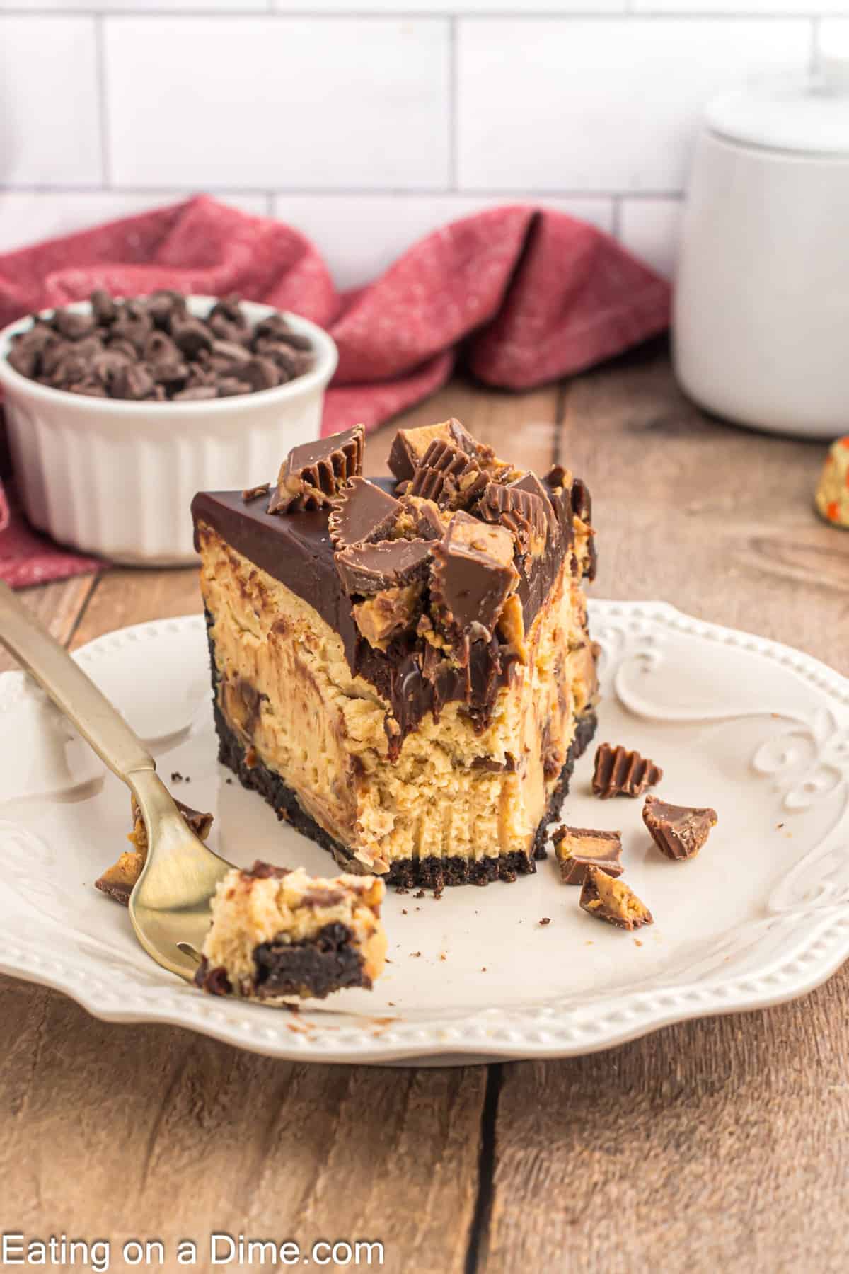 Slice of Reese's Cheesecake on a plate with a small bowl of chocolate chips on the side