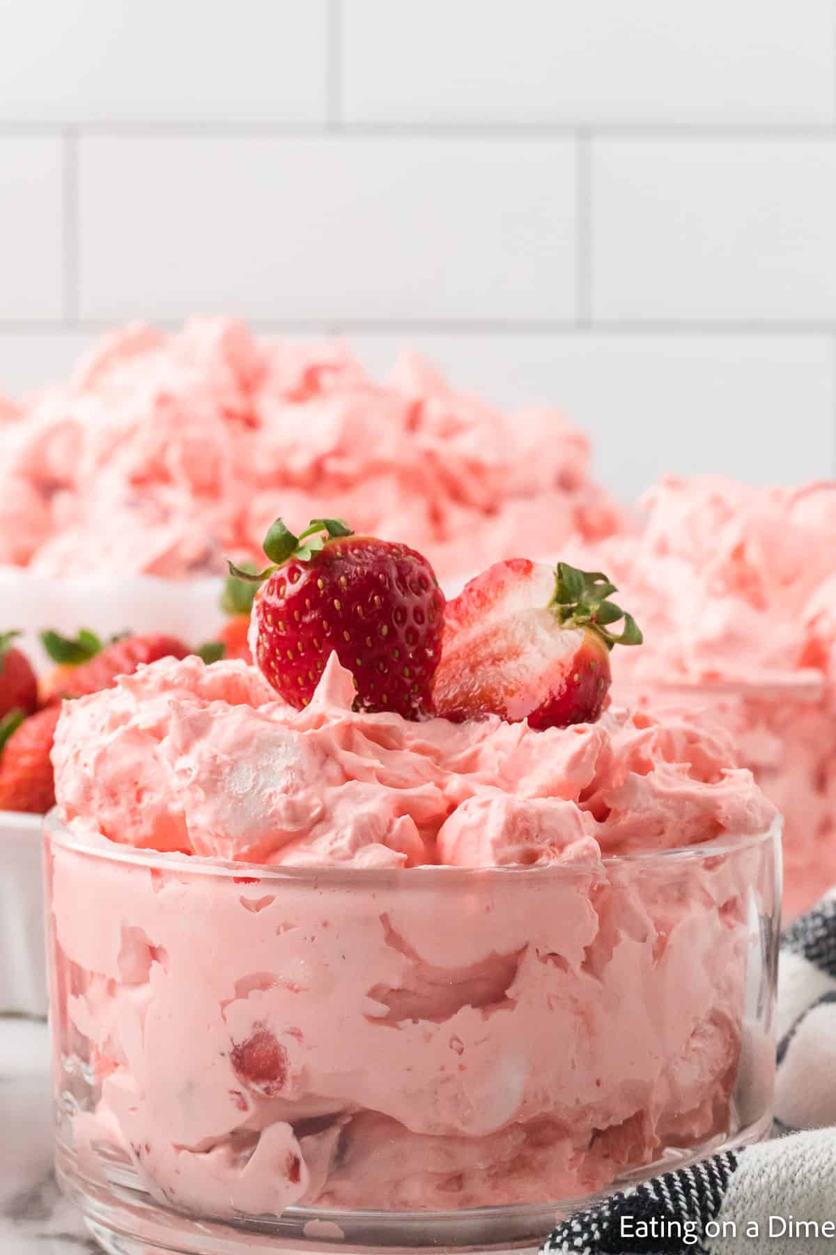 Strawberry Jello Salad in a clear bowl and topped with slice strawberries