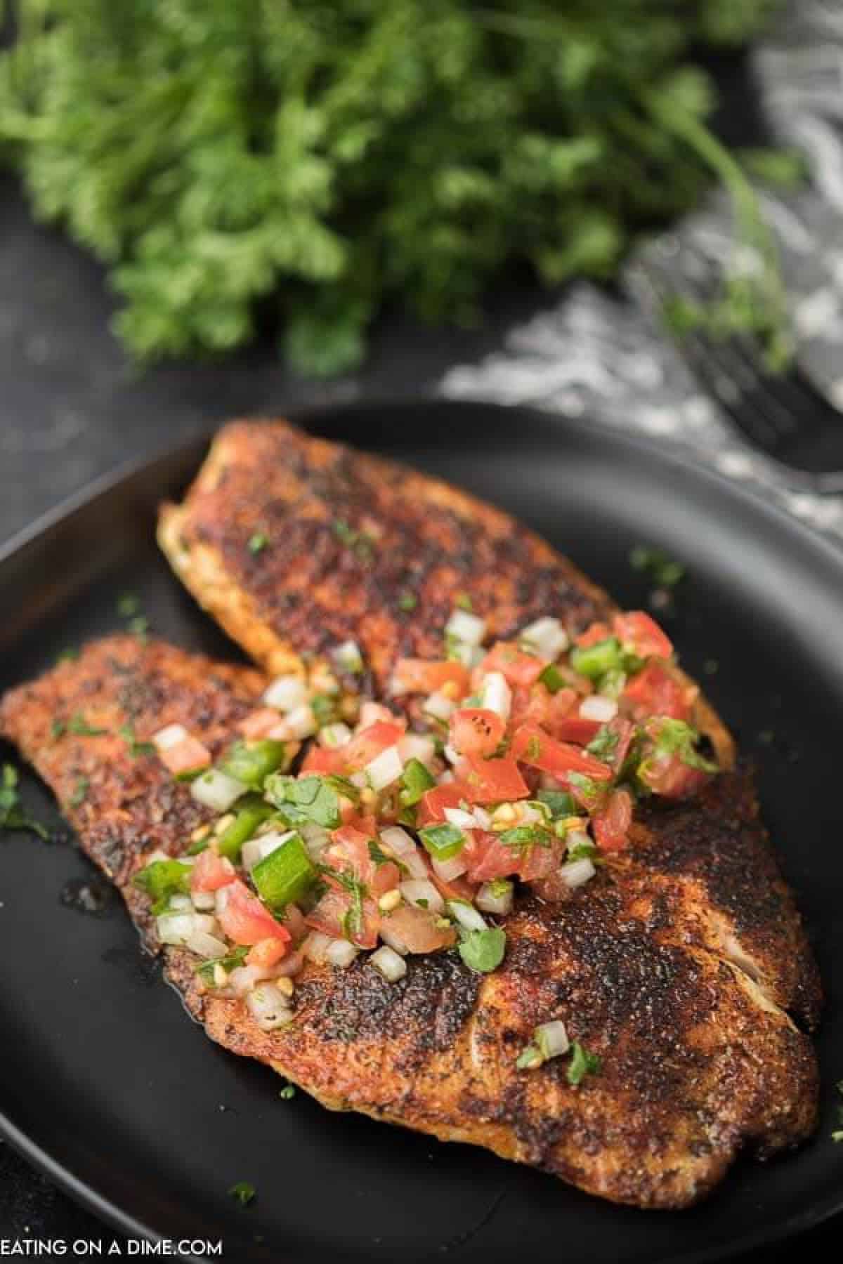 Close up image of blackened tilapia on a plate topped with pico