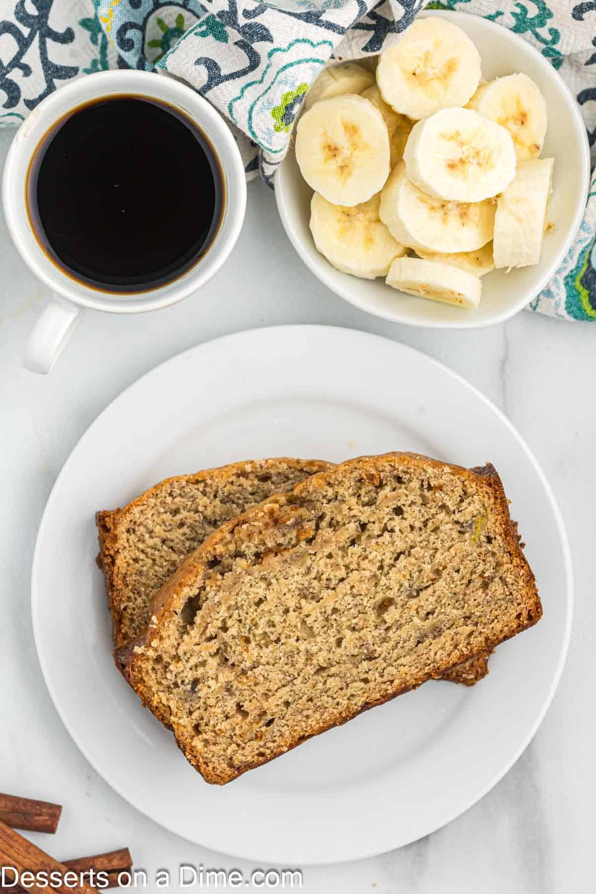 Slice brown sugar banana bread on a plate with a bowl of slice bananas and coffee