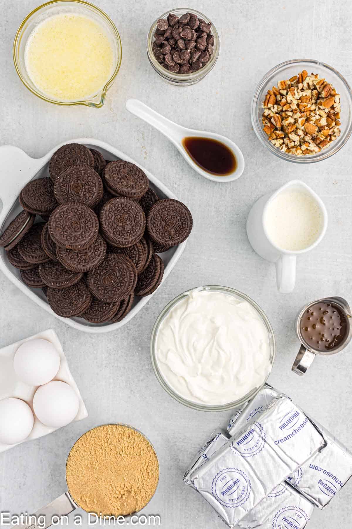 Ingredients - Oreo Cookies, melted butter, cream cheese, brown sugar, vanilla extract, sour cream, eggs, heavy cream, chocolate chips, caramel sauce, pecan halves