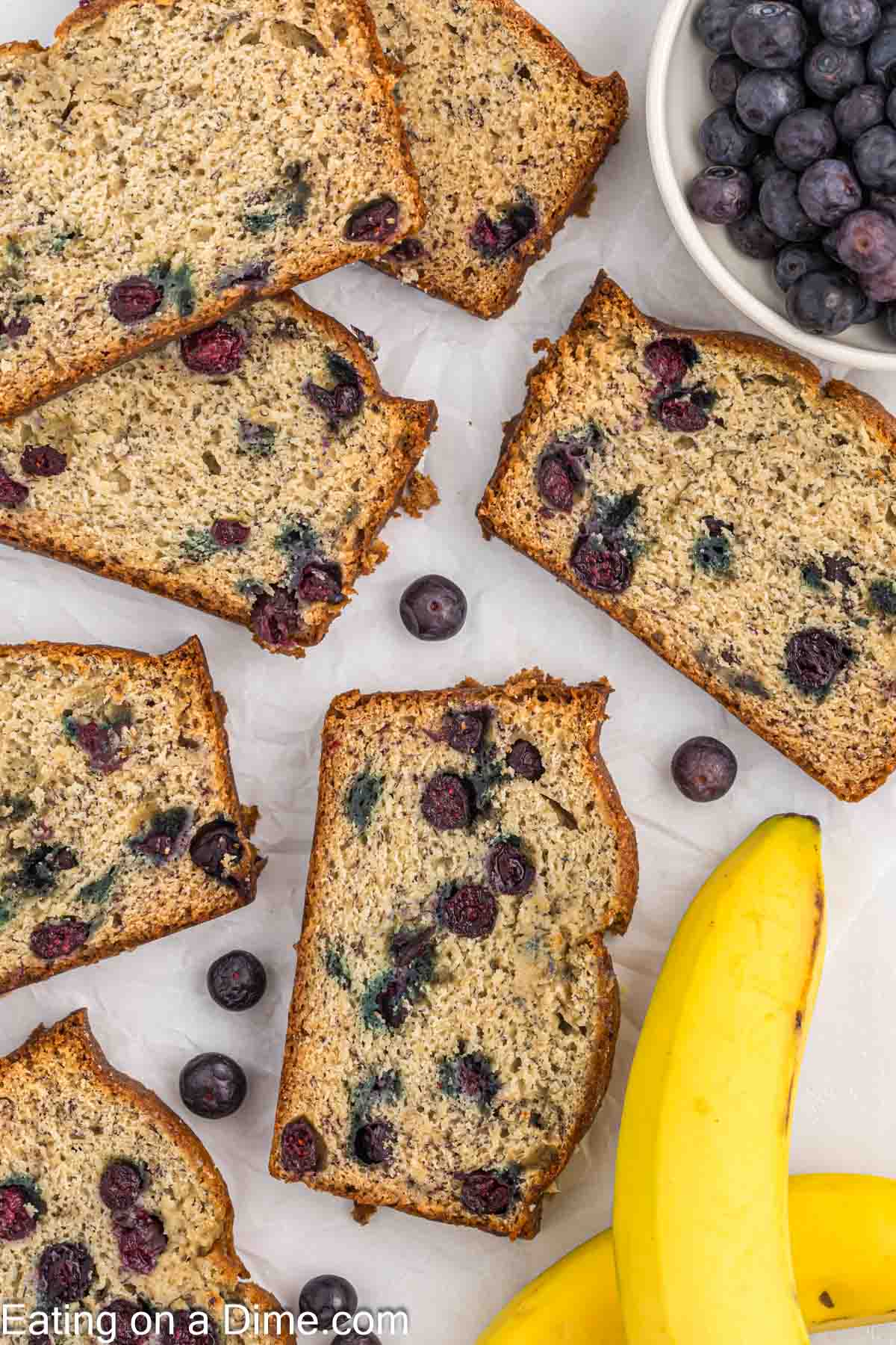 Blueberry banana bread slices with a bowl of blueberries on the side 