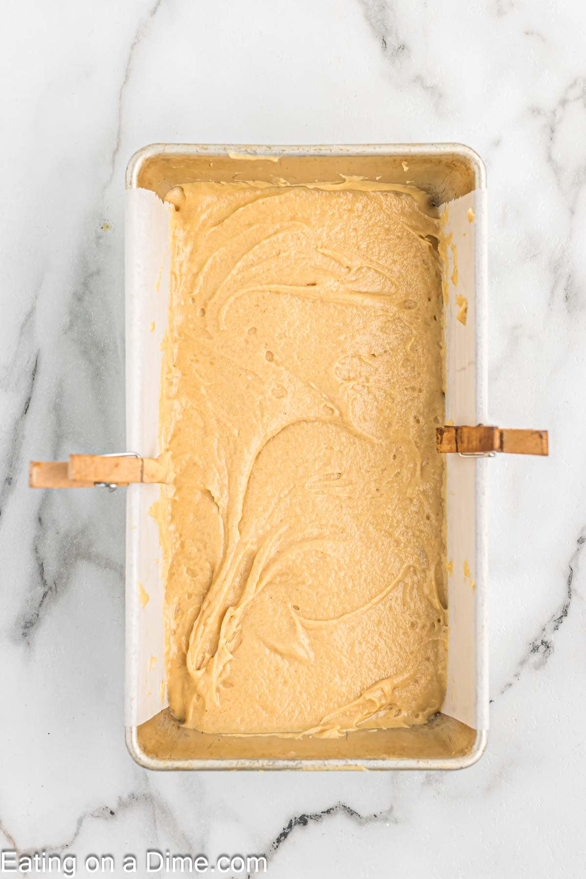 Peanut butter batter poured in loaf pan covered with parchment paper