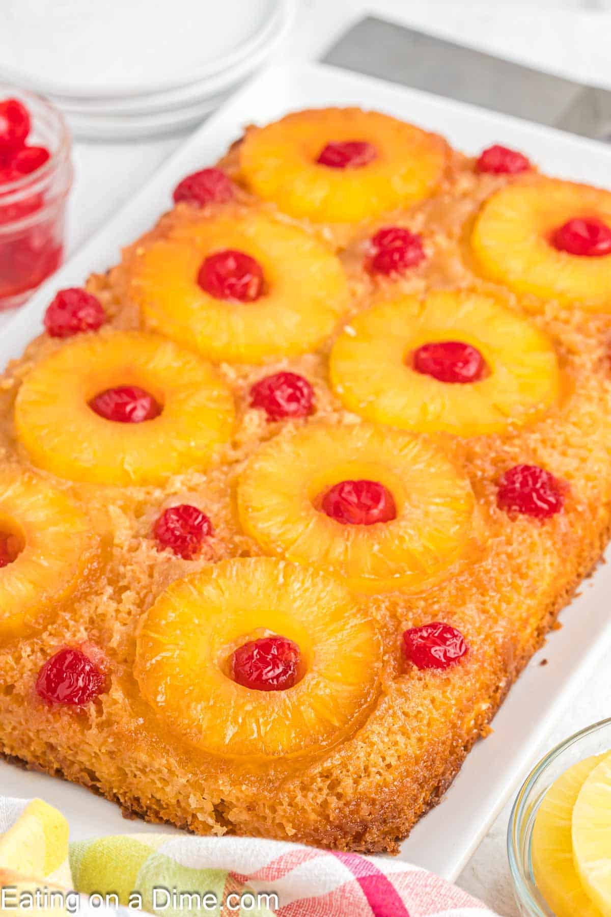 Pineapple upside down cake topped with pineapple slices and cherries on a platter