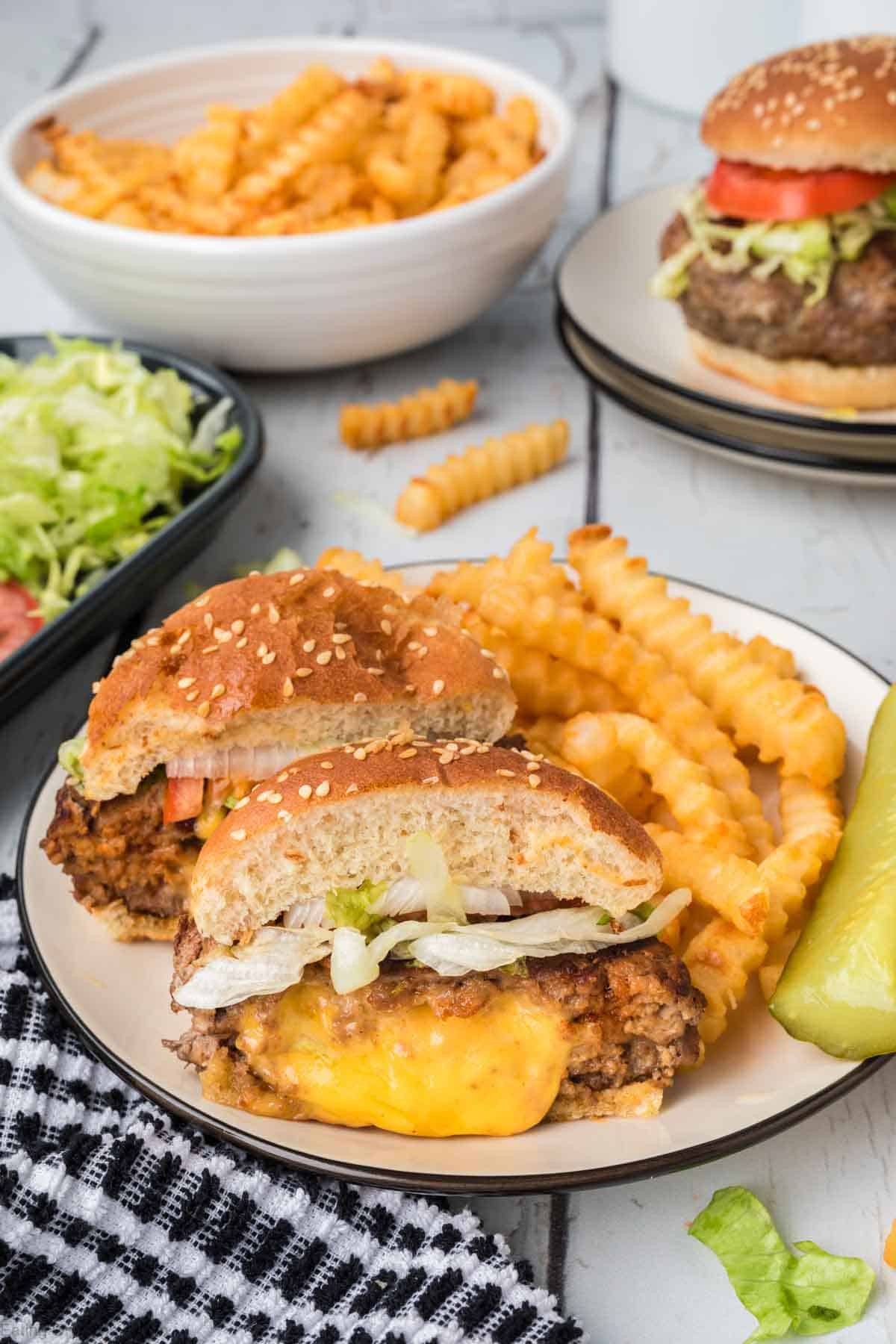 Juicy Lucy Burger cut in half on a plate with french fries
