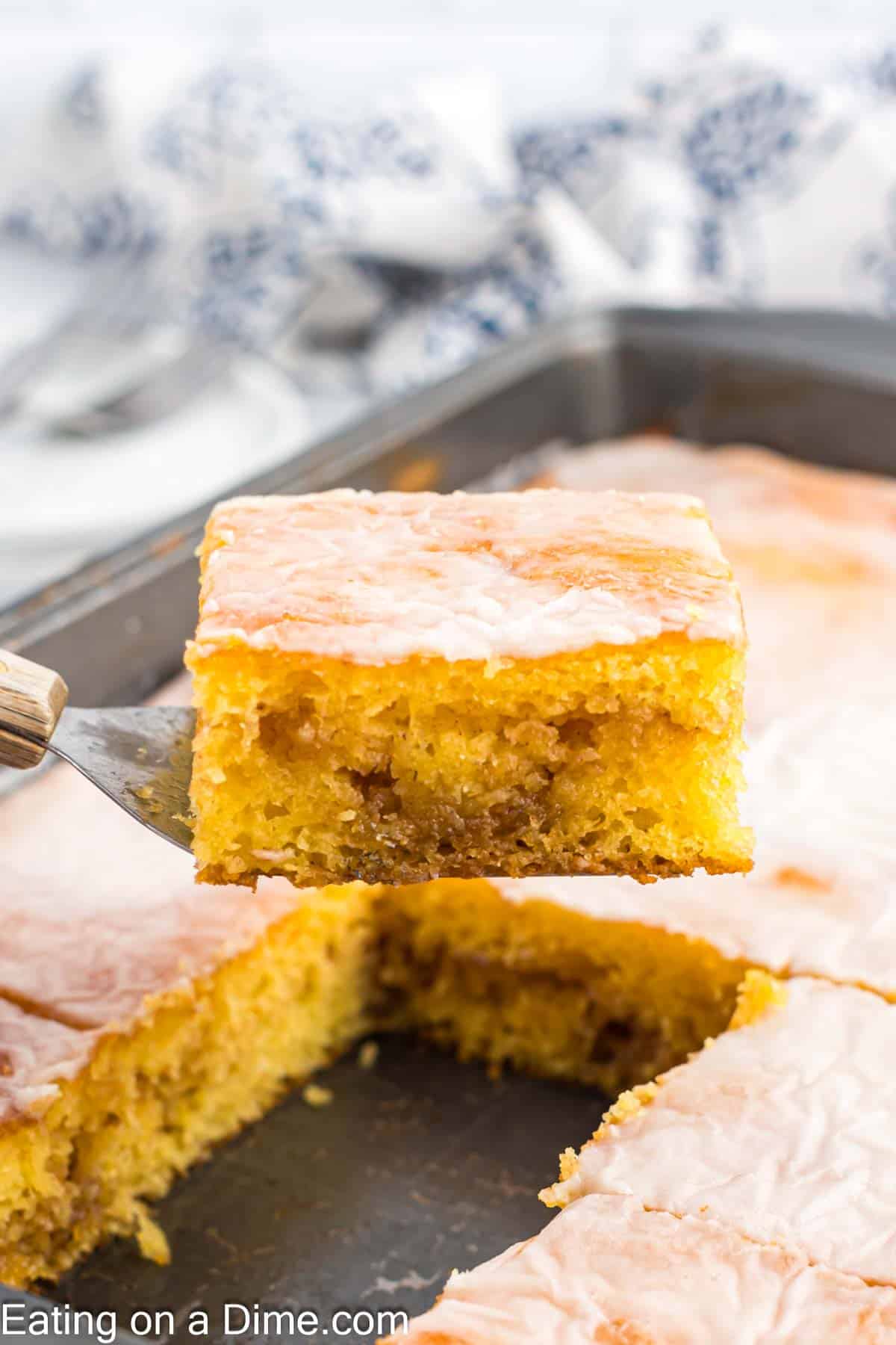 Honey Bun Cake in a baking dish sliced with a serving on a spatula