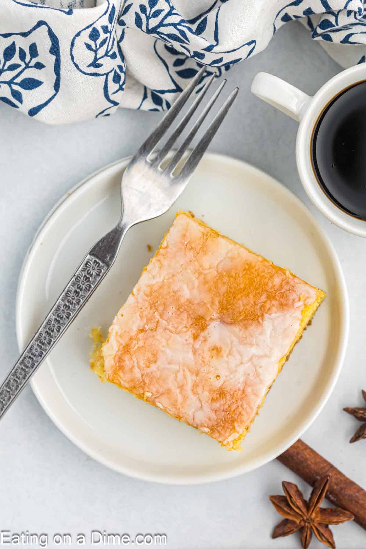 Square piece of honey bun cake on a plate with a fork