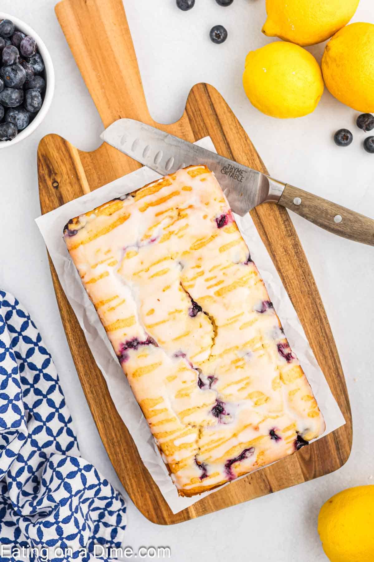 Lemon blueberry bread on a cutting board with parchment paper and a knife