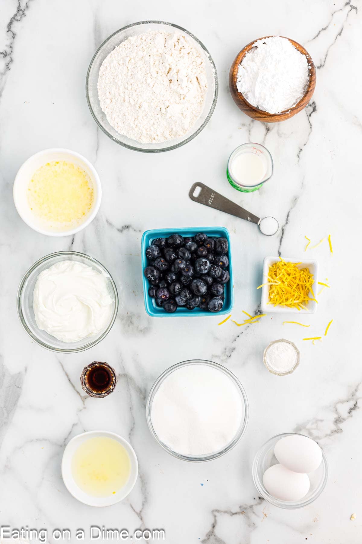 Ingredients - flour, baking powder, salt, sugar, lemon, butter, greek yogurt, eggs, vanilla extract, blueberries, powdered sugar, milk