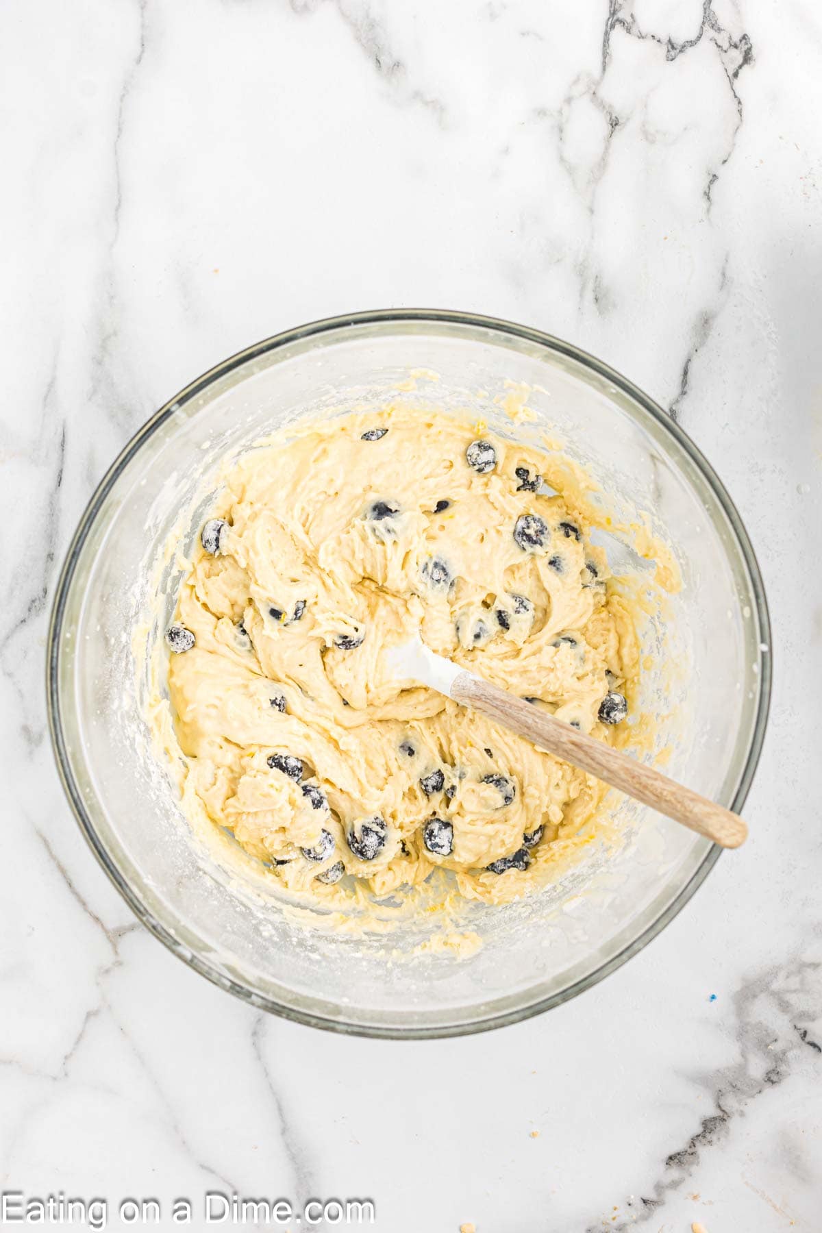 Lemon blueberry batter in a bowl with a wooden spoon