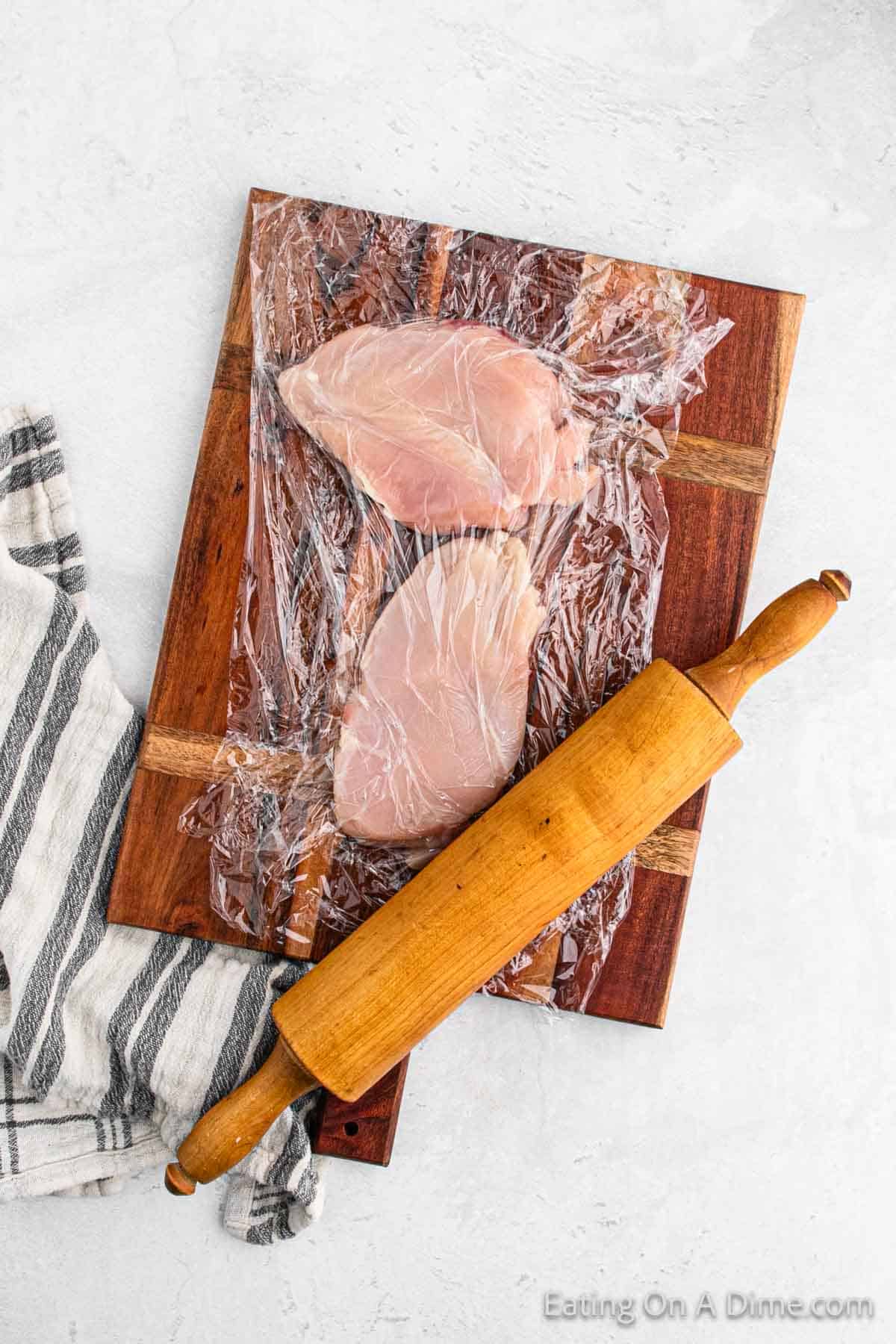 Pounding the chicken breast with a rolling pin on a cutting board