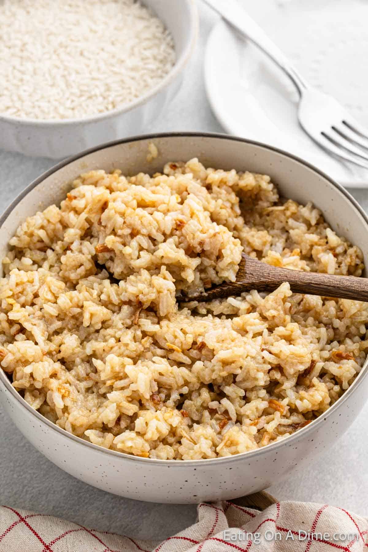 Butter rice in a bowl with a wooden spoon