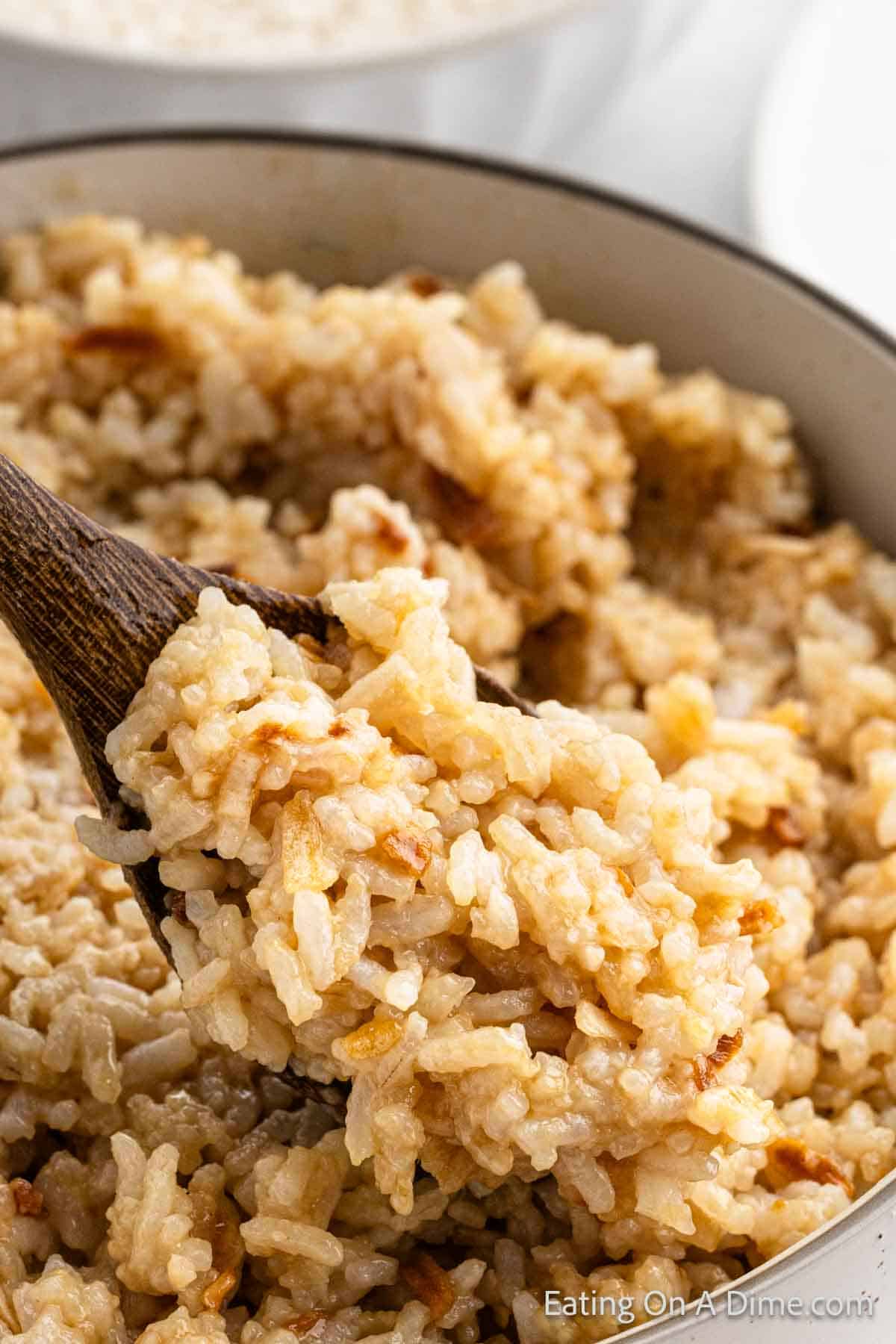 Butter rice in a large pot with a serving on a wooden spoon