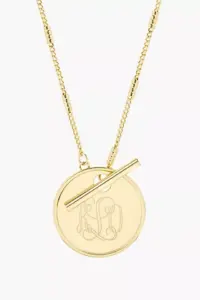 This exquisite gold necklace, perfect for Mother's Day gifts, features a circular pendant with the engraved initials "K O." The chain boasts detailed links and a horizontal bar elegantly crossing the top of the pendant.