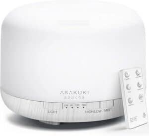 A white essential oil diffuser with a sleek cylindrical design, perfect for Mother's Day gifts. It features a digital timer, buttons for light and high/low mist settings, and comes with a separate remote control. The brand name "ASAKUKI" is elegantly printed on the front.