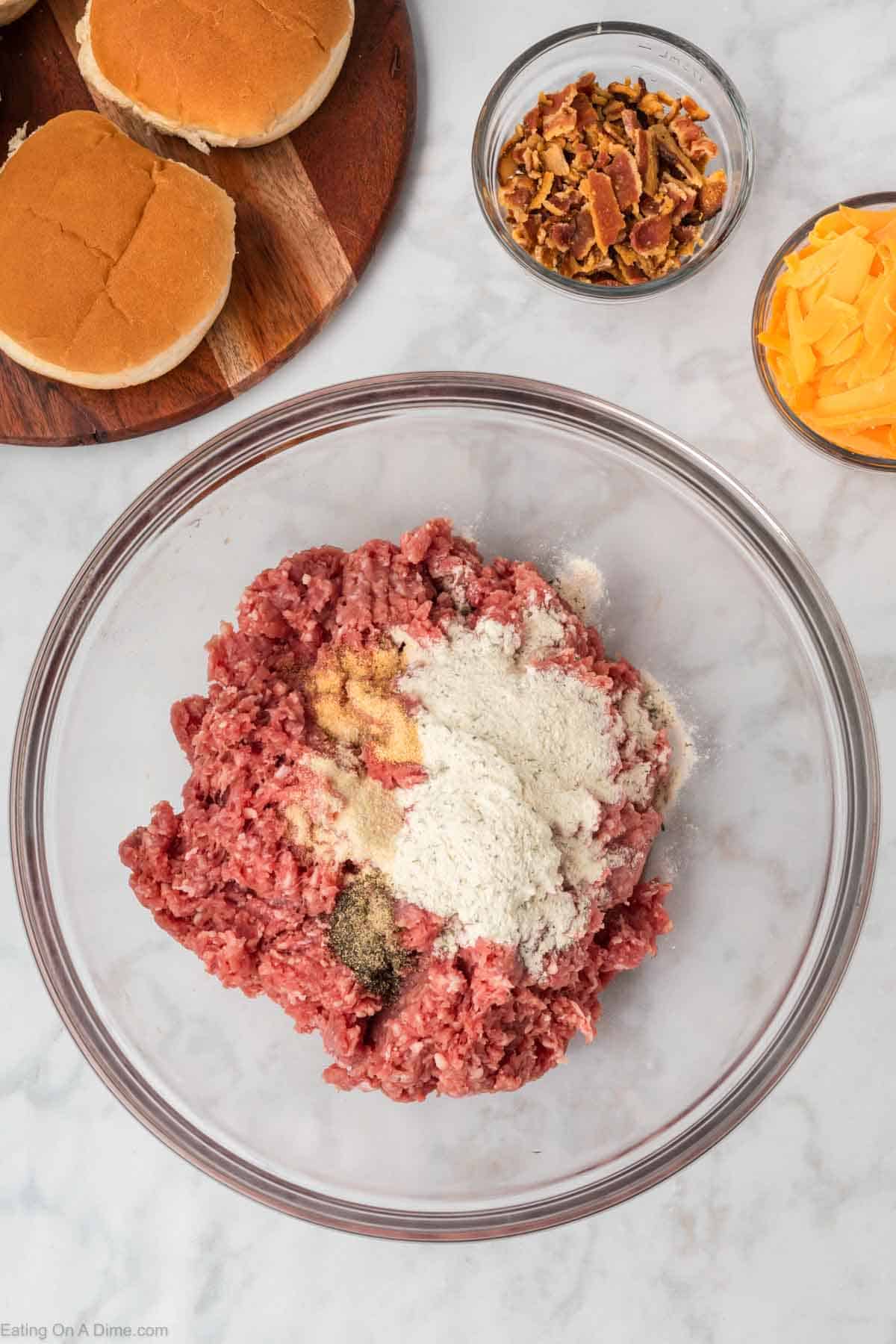 Combining ground beef in a bowl with ranch seasoning, pepper, garlic powder