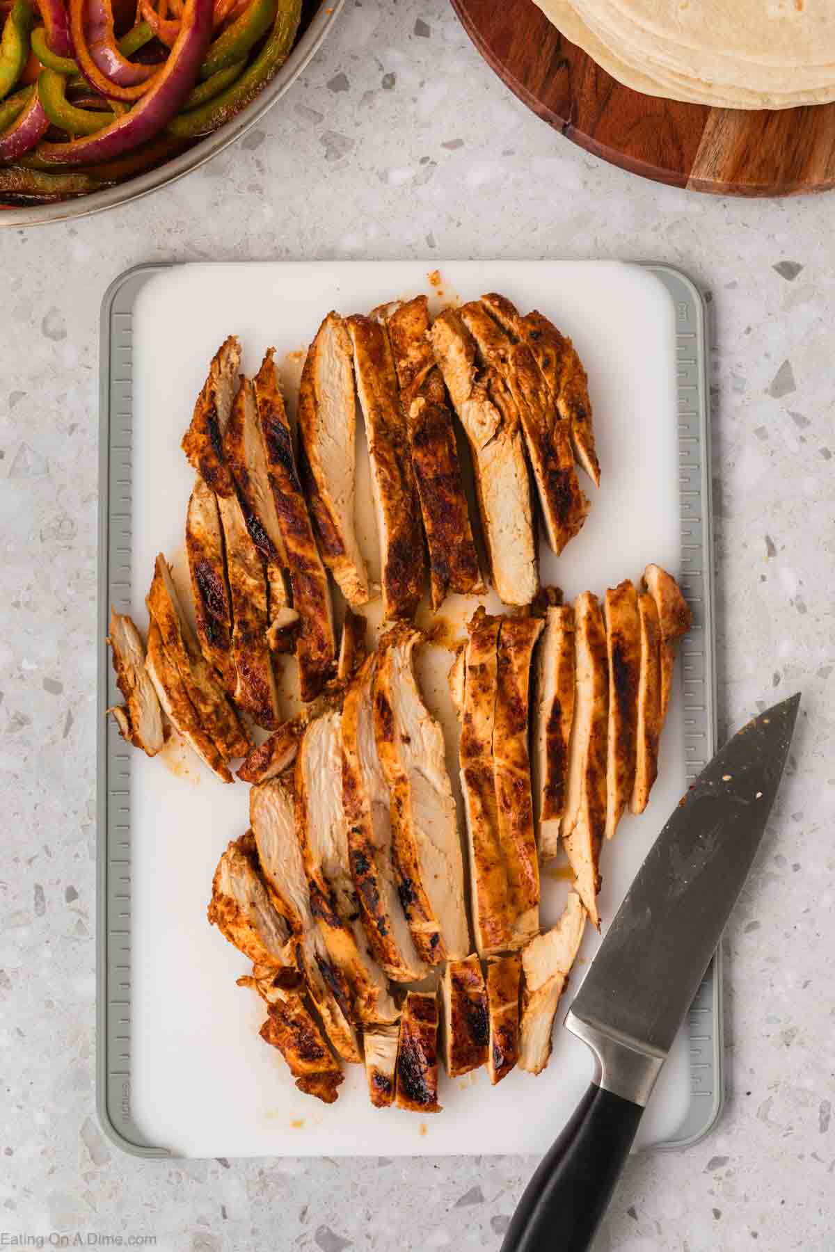 Chicken breast cut into strips on the cutting board with a knife