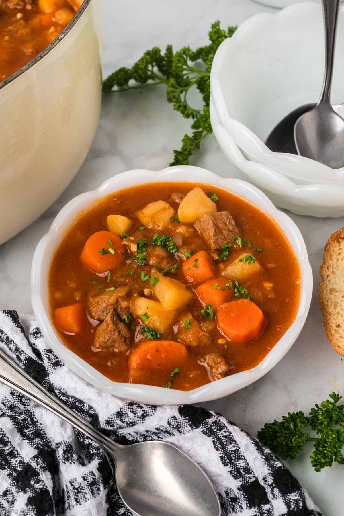 Hungarian Goulash in a white bowl loaded with beef stew, carrots, and potatoes in a red broth