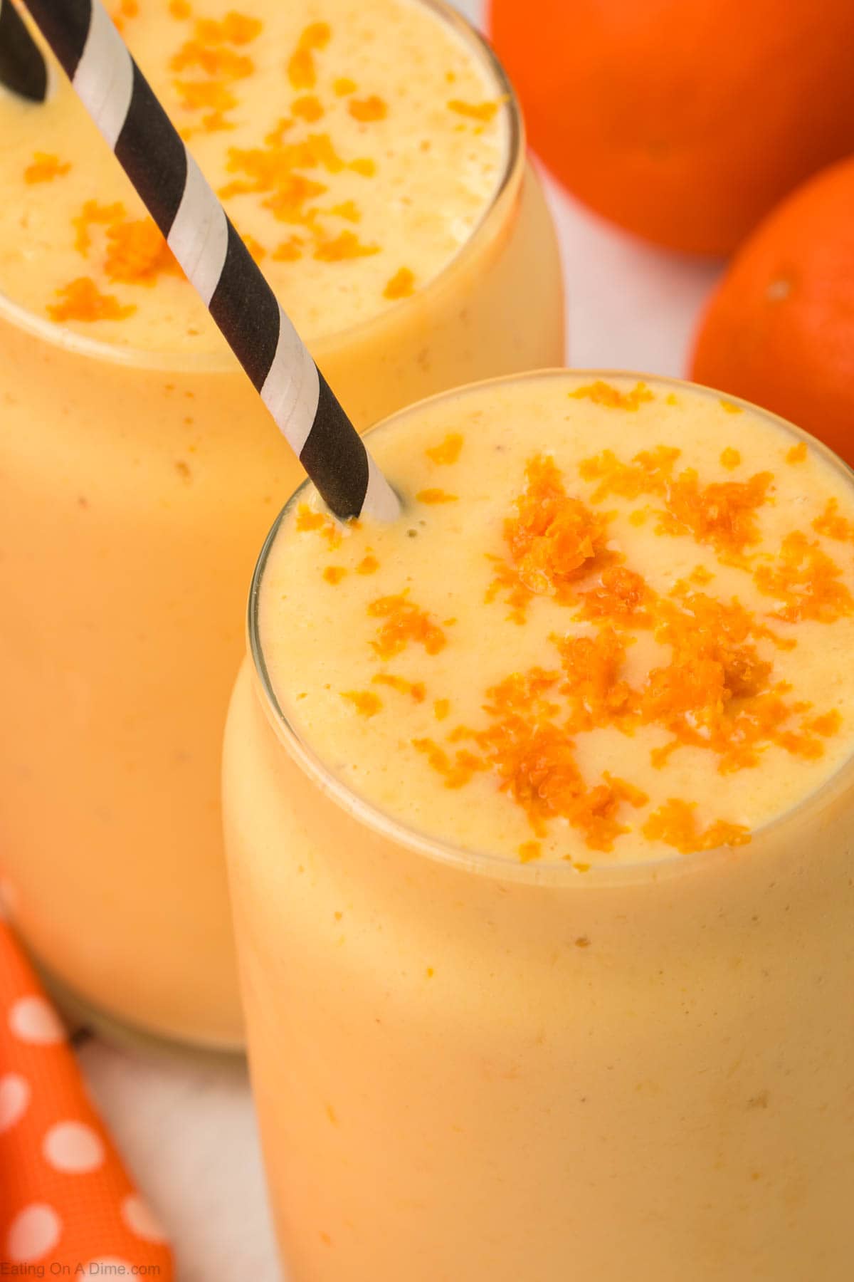 Orange Smoothie in a clear glass topped with orange zest