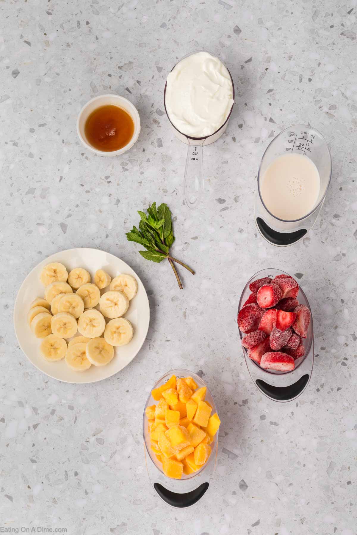 Strawberry mango smoothie ingredients - banana, mango, strawberries, milk, yogurt, fresh mint and honey