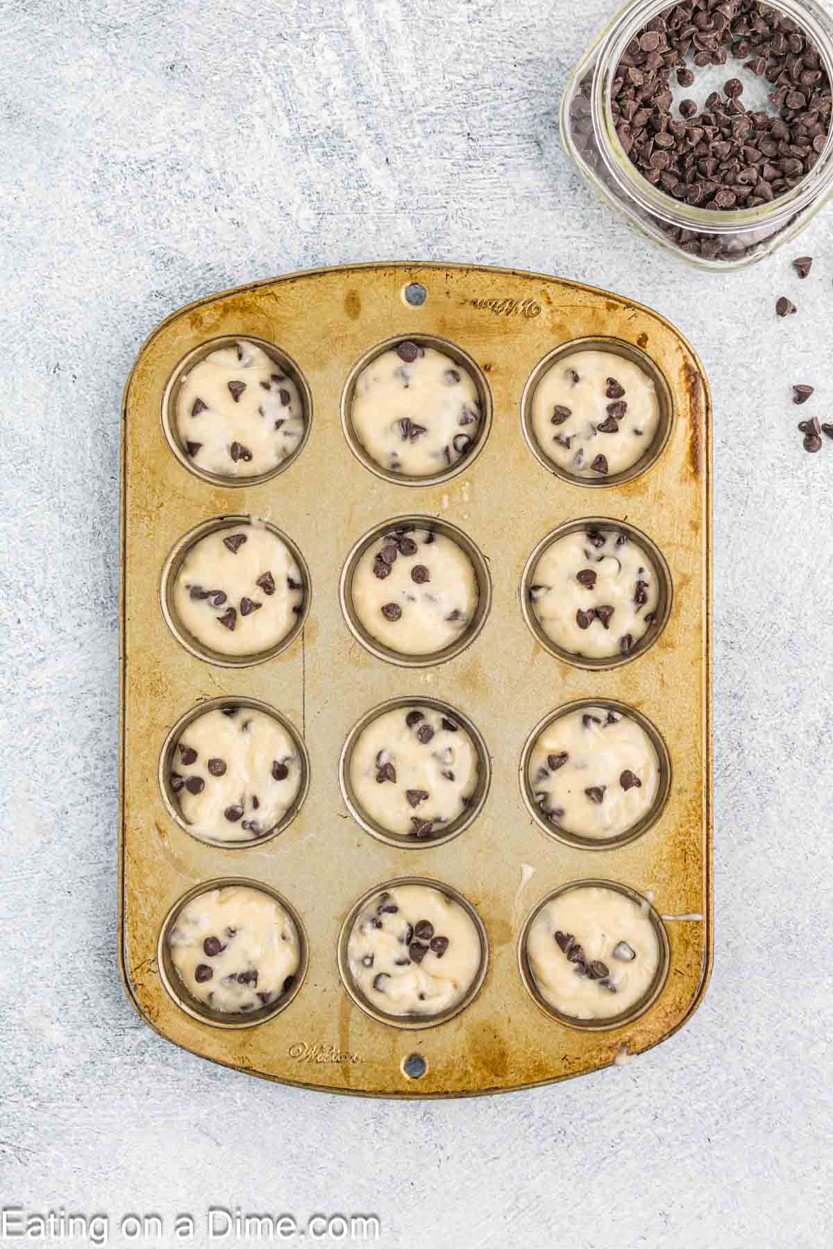 Placing the chocolate chip muffin batter in the muffin pan