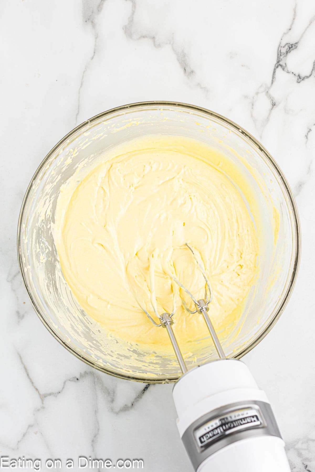 Combining the cake, pudding mix, eggs, and oil with a hand mixer in a bowl