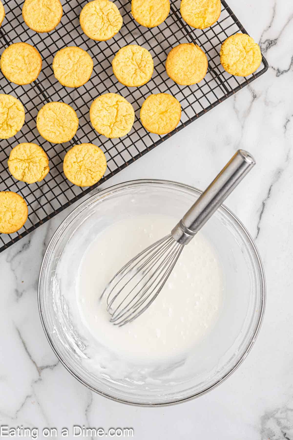 combining the lemon glaze in a bowl with lemon blossoms on a wire rack