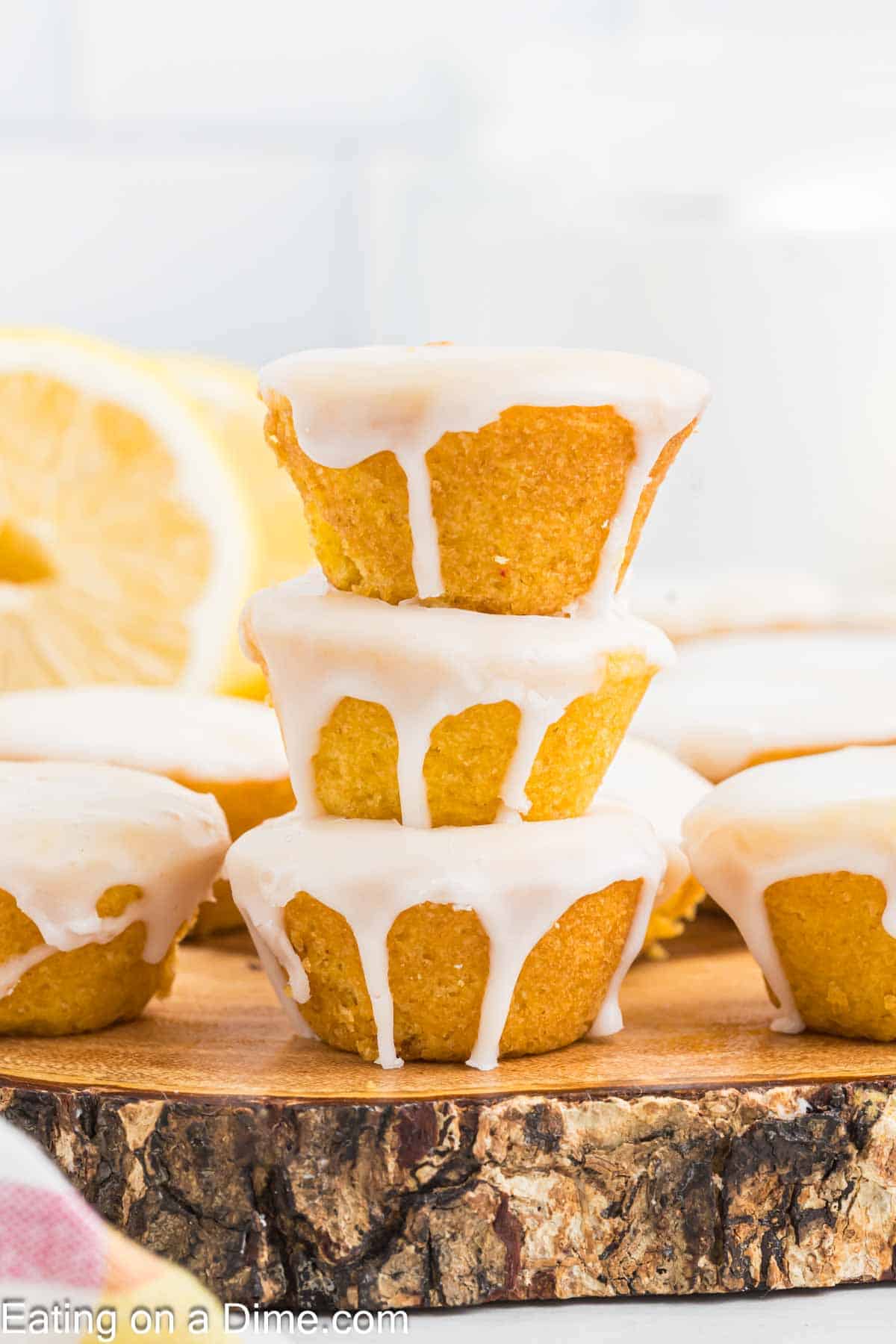 3 Lemon Blossoms topped with glaze and stacked on a wooden serving dish with other lemon blossoms on the side