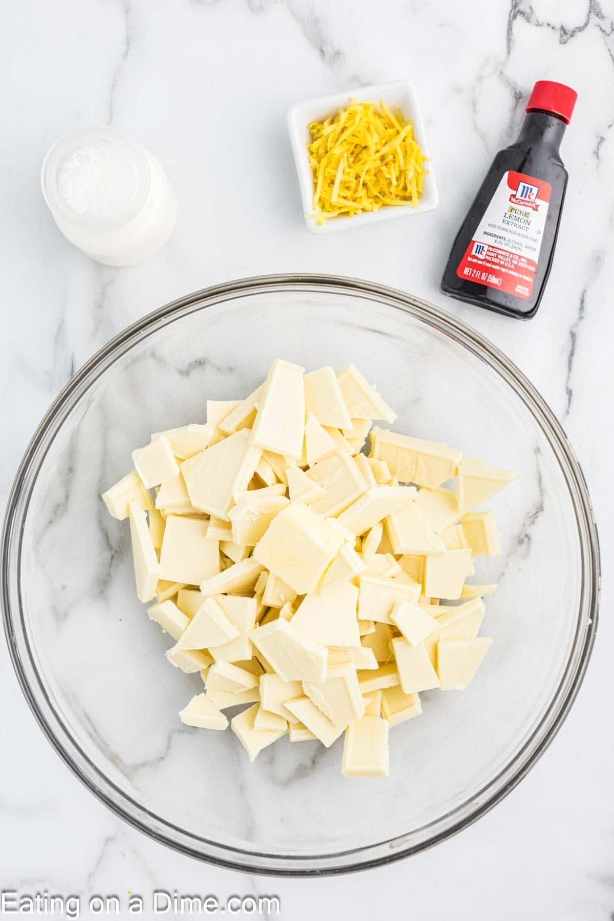 White chocolate pieces in a bowl with lemon zest strips in a bowl with lemon extract on the side