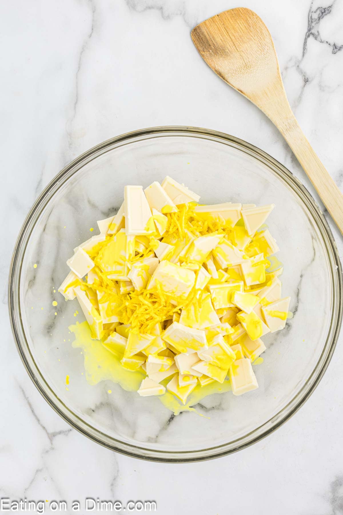 White chocolate pieces in a bowl topped with lemon heavy cream mixture