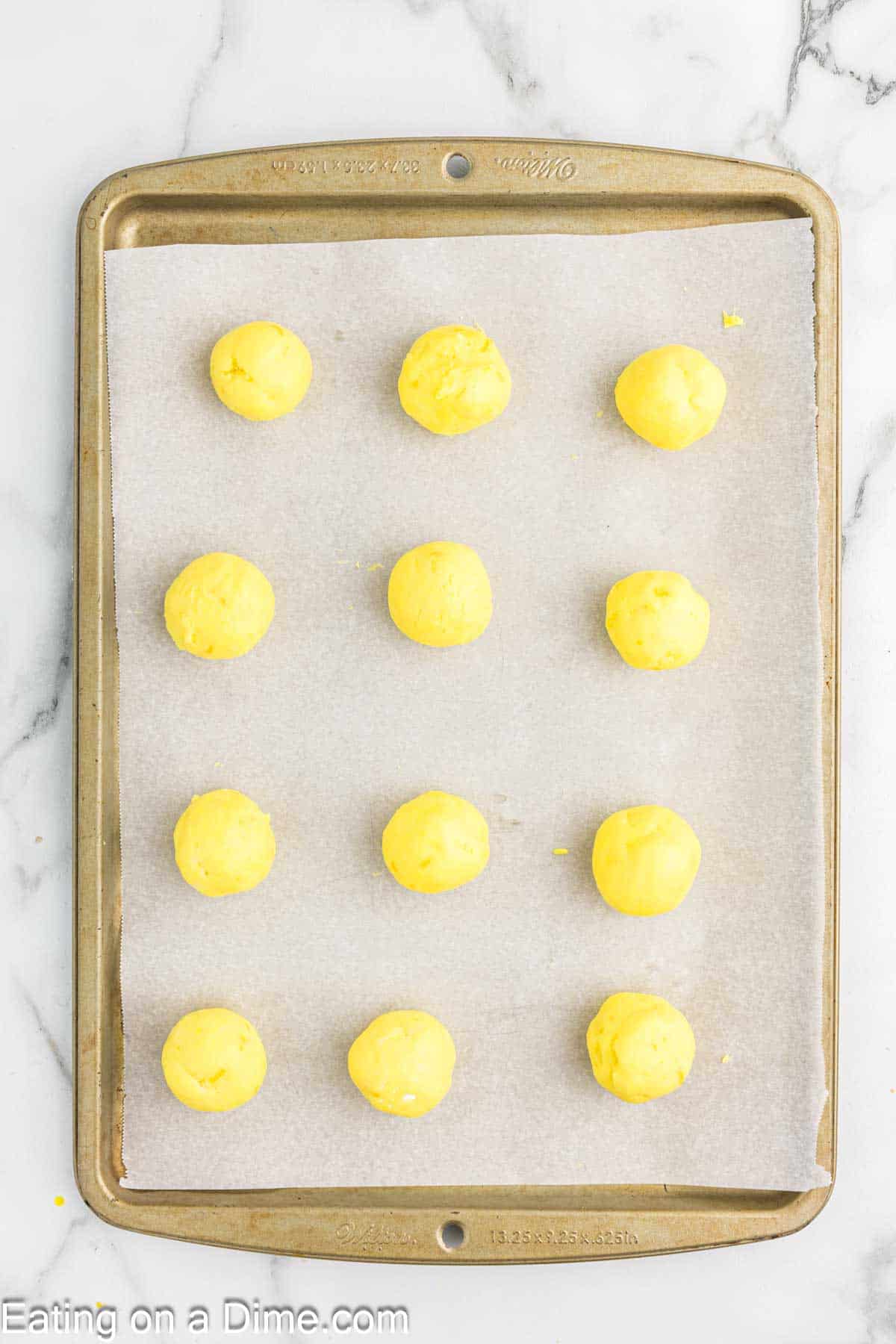 Lemon truffles mixture rolled into balls placed on a baking sheet lined with parchment paper