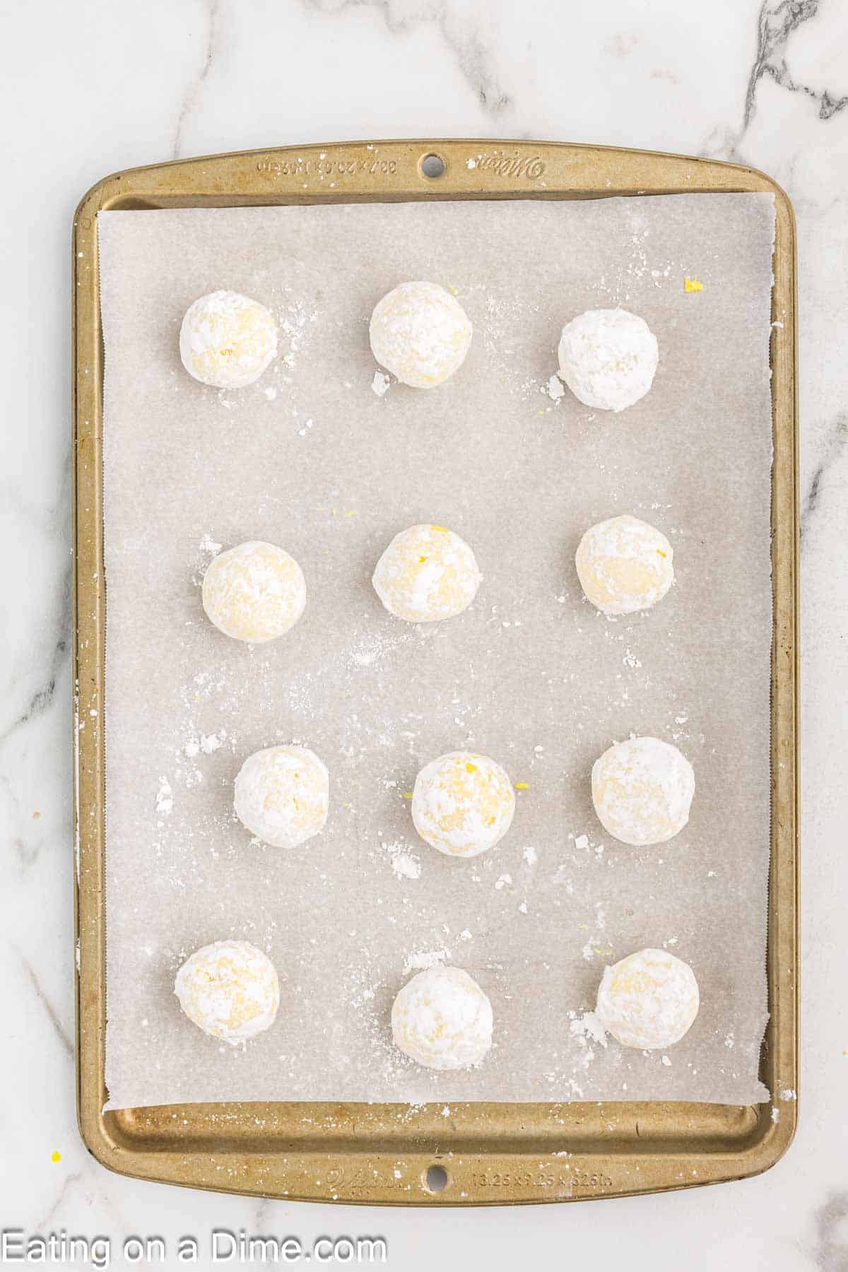 Lemon Truffles coated with powdered sugar placed on a baking sheet lined with parchment paper