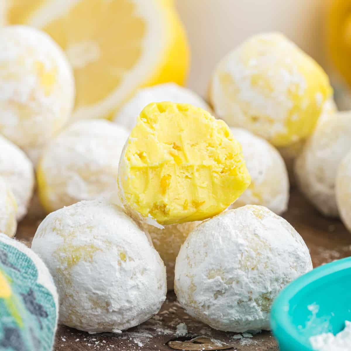 Lemon Truffles coated with powdered sugar stacked on a cutting board